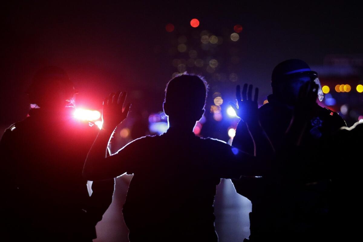 A protester raises his arms as California Highway Patrol officers stand in front of him during a demonstration that blocked Interstate 80 in Berkeley on Dec. 8.