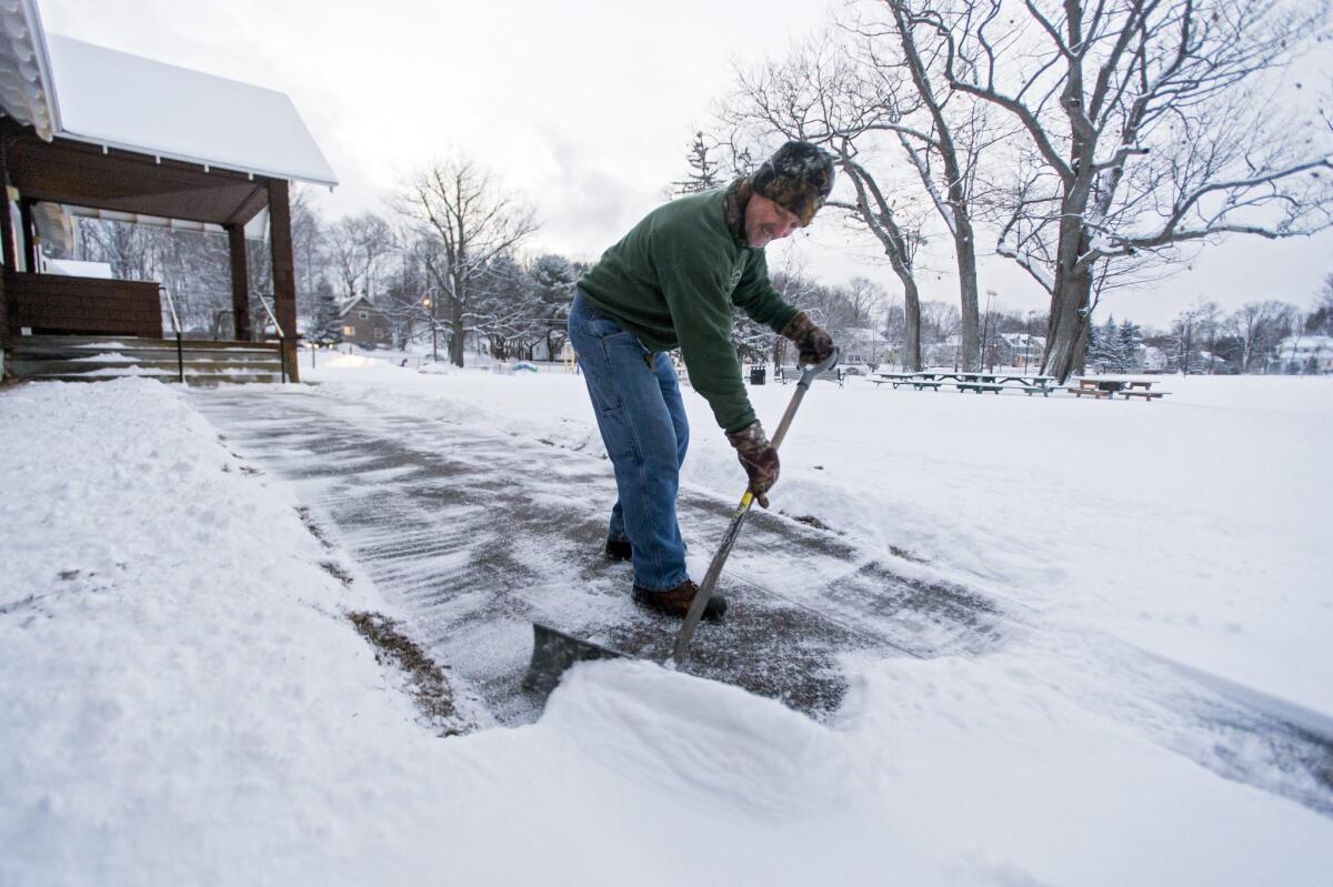 Wayne Peirce shovels snow off the sidewalk at a polling station in preparation for opening in Laconia, N.H.