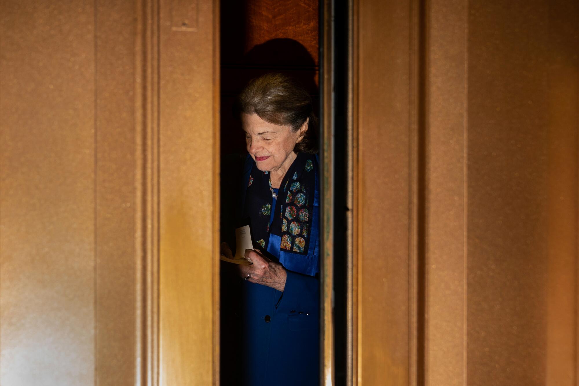 Sen. Dianne Feinstein is seen through a flash-lit door opening, slightly smiling with her eyes closed.