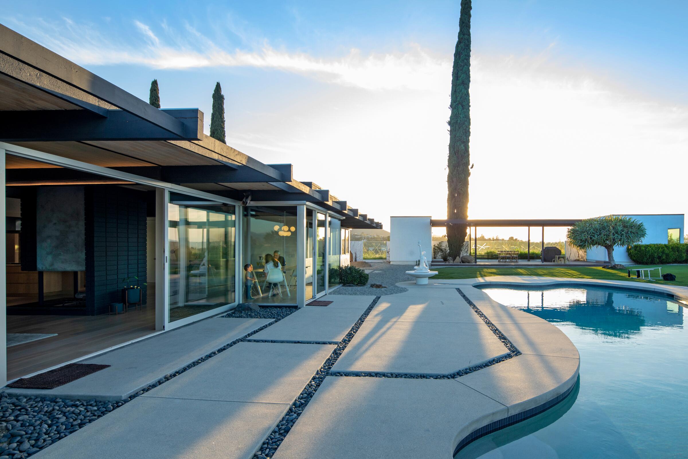 A sweeping sunset view of a Neutra-designed home's backyard with a pool.