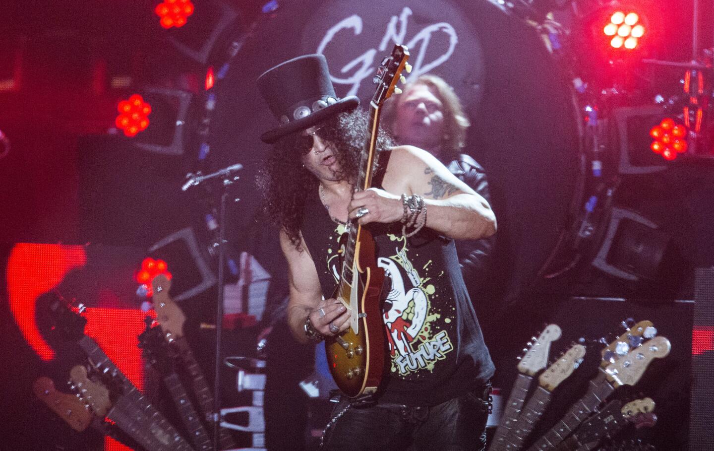 Lead guitarist Slash (with singer Axl Rose behind him) and their band Guns N Roses onstage at the Coachella Valley Music and Arts Festival, 2016.