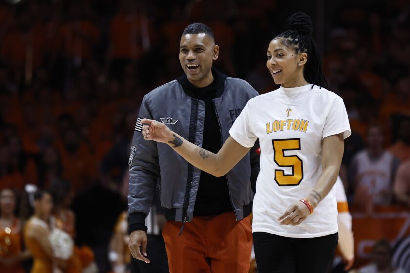 Former Tennessee basketball players Alan Houston and Candace Parker walk to the court as they were on hand for the retiring of former player Chris Lofton's jersey at an NCAA college basketball game against Kentucky, Saturday, Jan. 14, 2023, in Knoxville, Tenn. (AP Photo/Wade Payne)