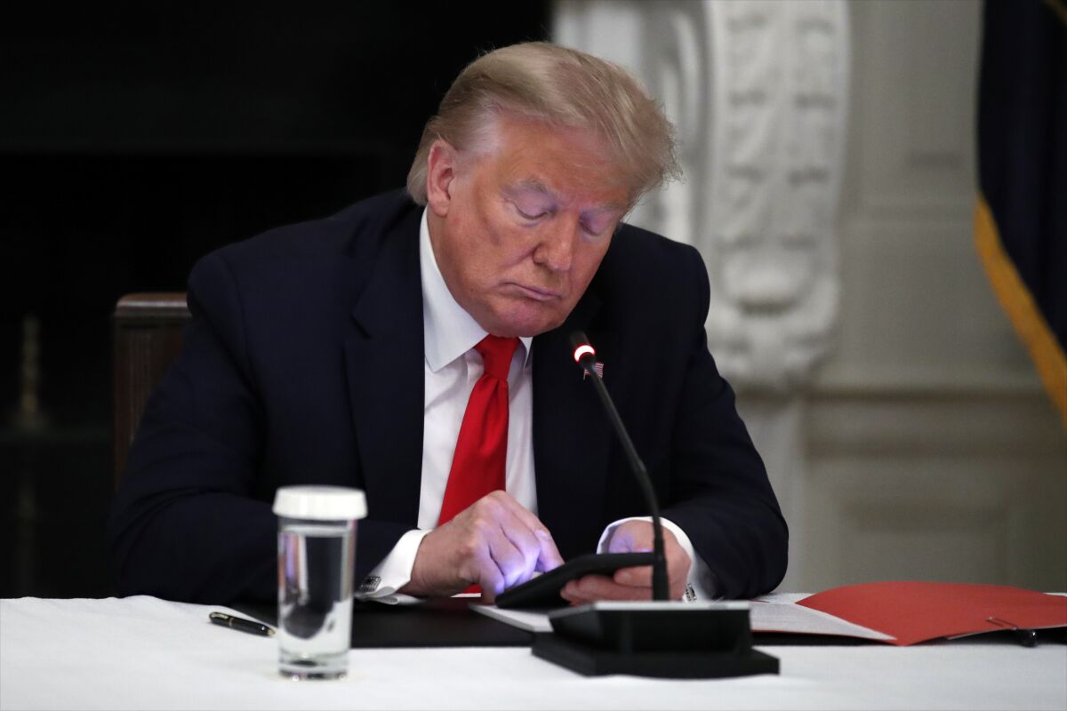  President Donald Trump looks at his phone.