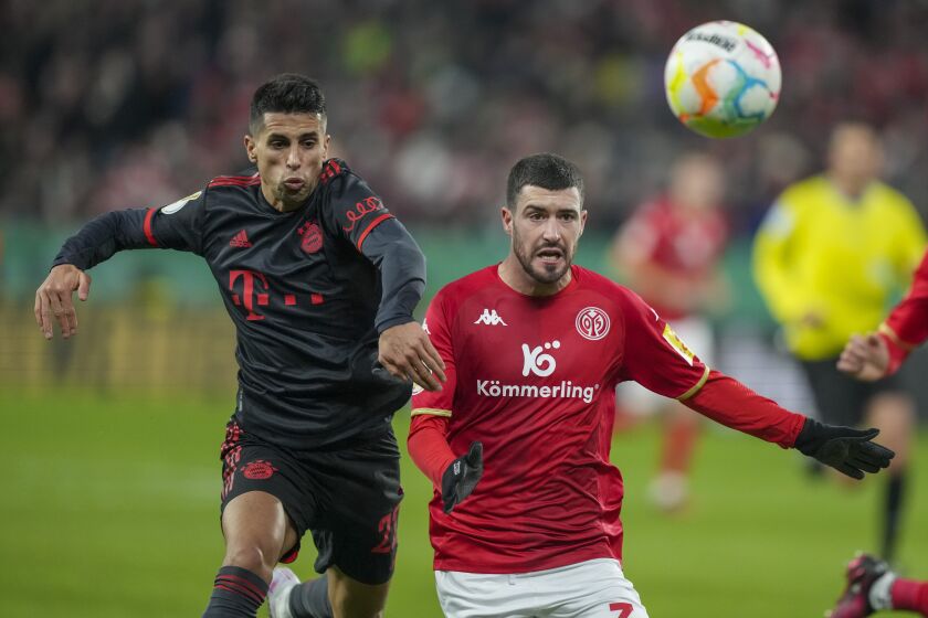 CORRECTS NAMES AND DATE --- Bayern's Joao Cancelo, left, and Mainz's Aron Martin, right, fight for the ball during a German Cup round of 16 Soccer match between FSV Mainz 05 and Bayern Munich, in Mainz, Germany, Wednesday, Feb. 1, 2023. (AP Photo/Michael Probst)