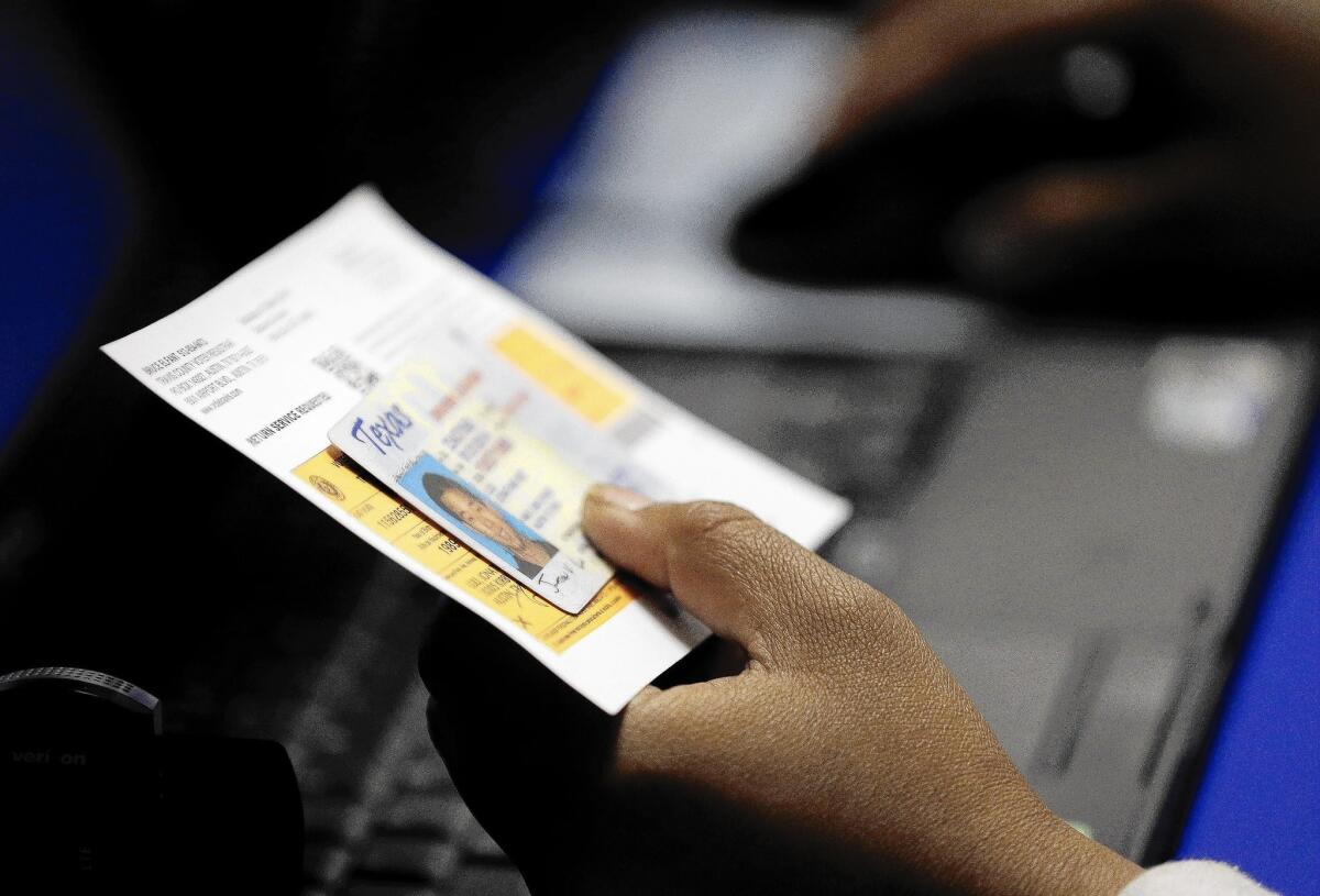 An election official checks a voter's ID at a polling station. In 2010, two states required photo IDs at polls; this fall, almost a dozen states will require them.