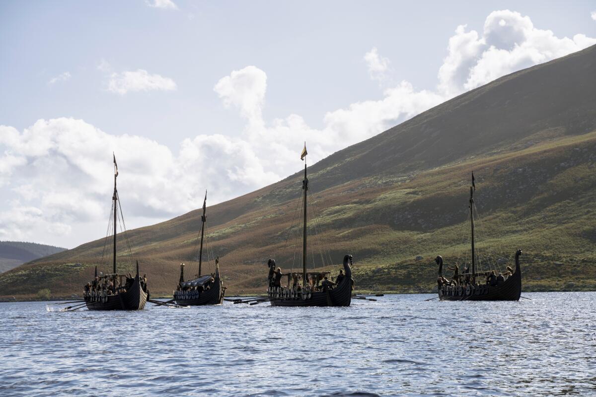 Viking ships on the water near rolling green hills