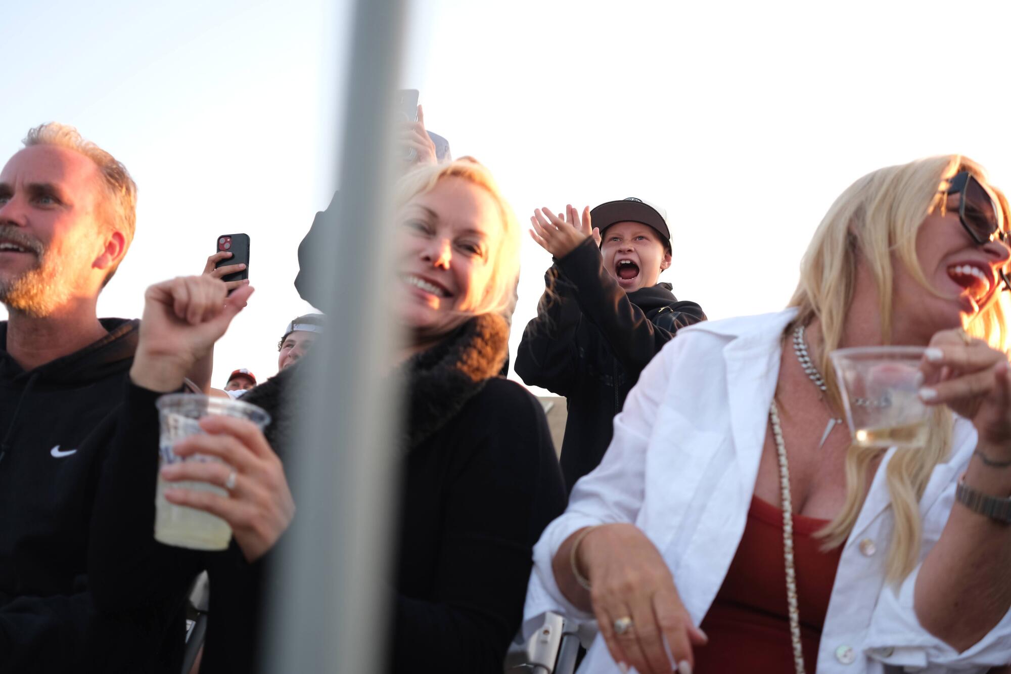 Two blond women holding white wine and a man and child in black laugh and cheer.