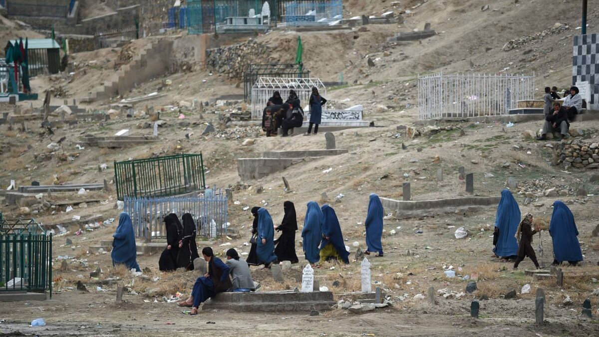 Afghan women walk through a cemetery near the old fortress of Bala Hissar in Kabul on March 23.
