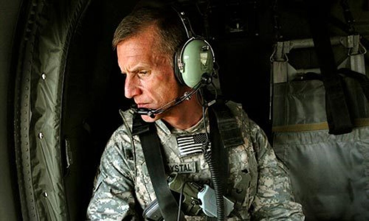Gen. Stanley McChrystal, wearing fatigues and a headset, looks out a window while riding in an aircraft.