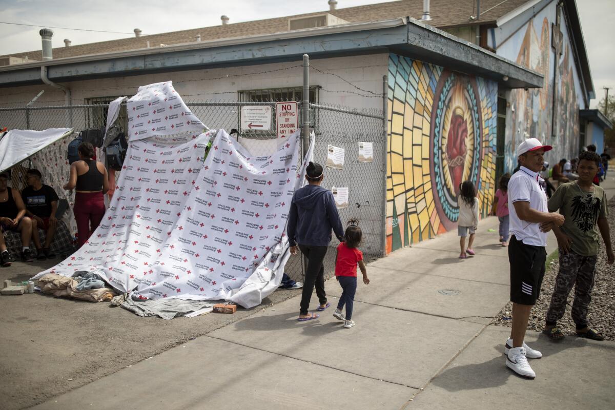 A group of migrants in the alley outside the makeshift migrant shelter at Sacred Heart Church in El Paso