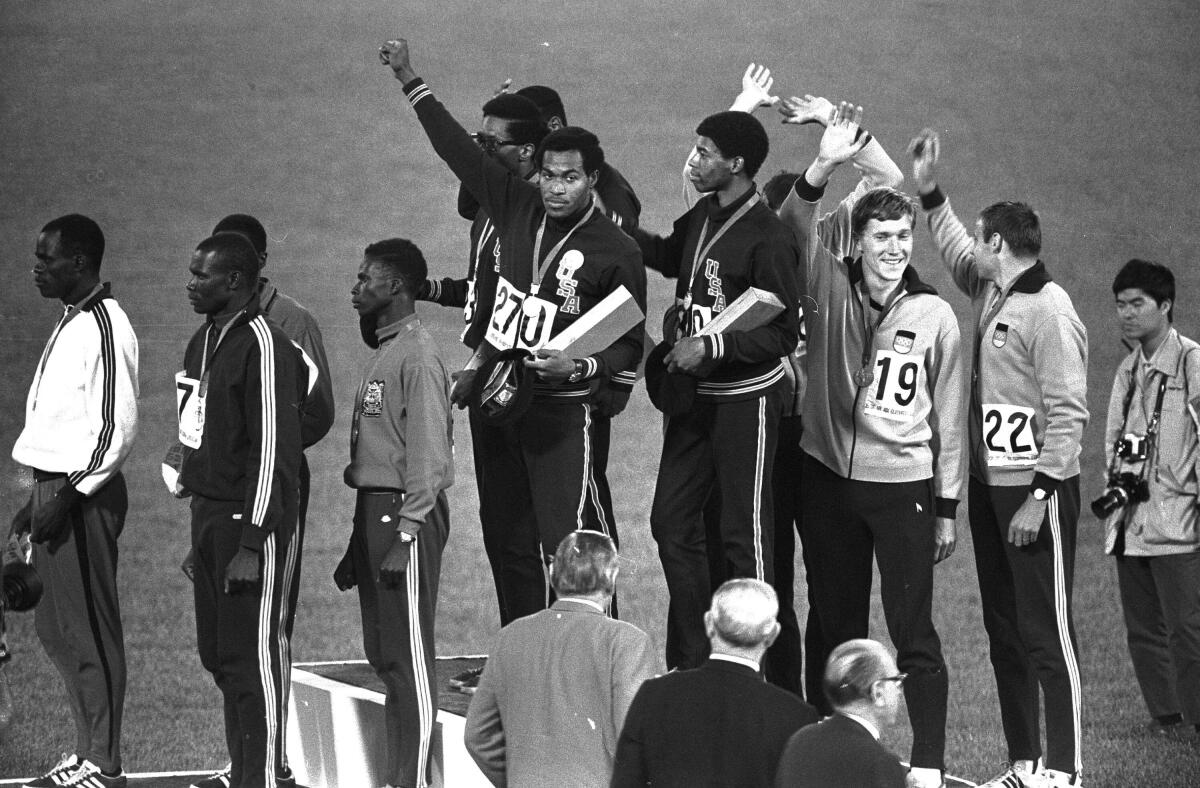 Lee Evans holds up a fist after receiving his gold medal at the 1968 Olympics.
