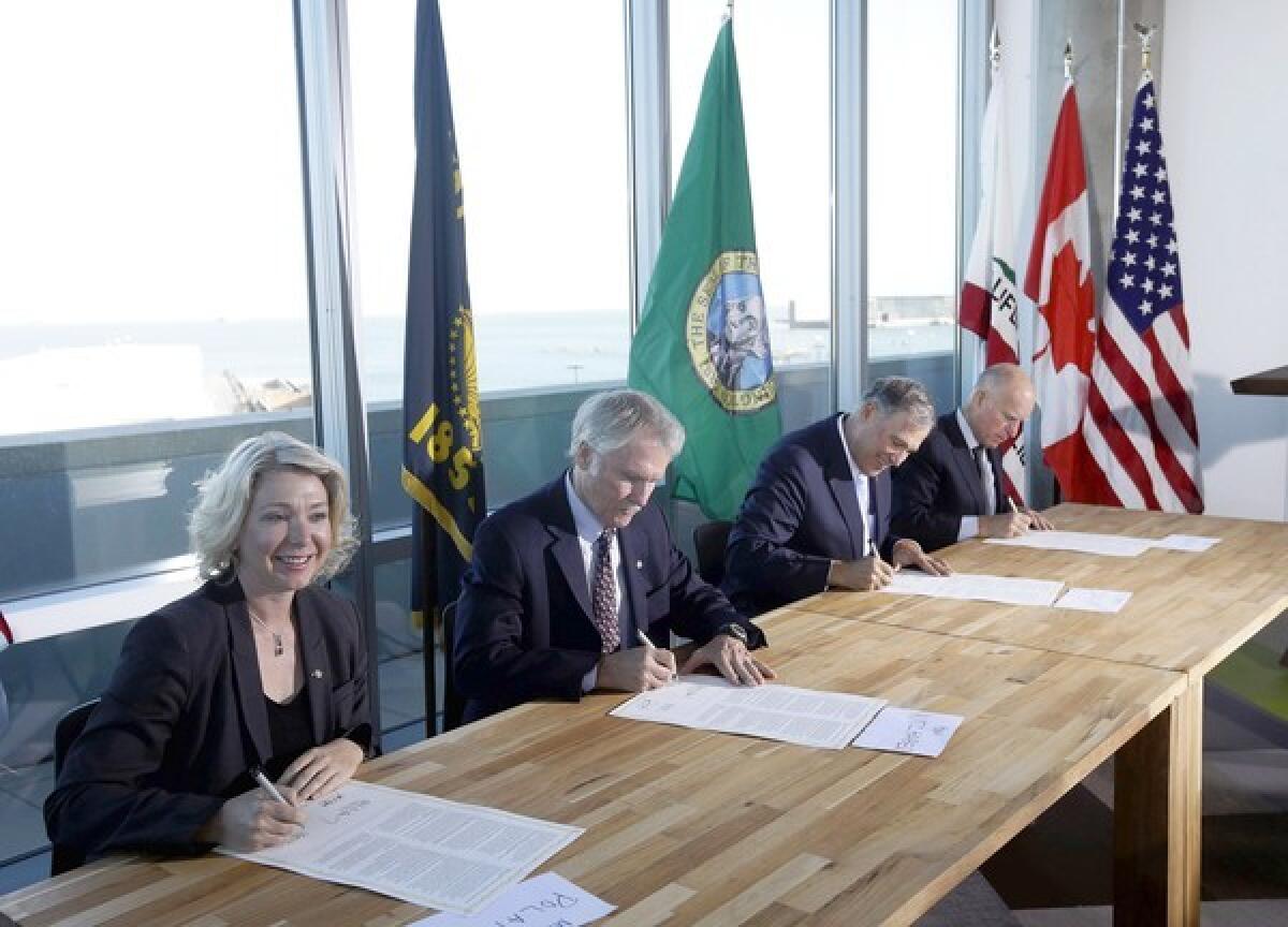 From left, Mary Polak, environment minister of British Columbia, Oregon Gov. John Kitzhaber, Washington Gov. Jay Inslee and California Gov. Jerry Brown sign an agreement to collectively combat climate change on Monday in San Francisco.