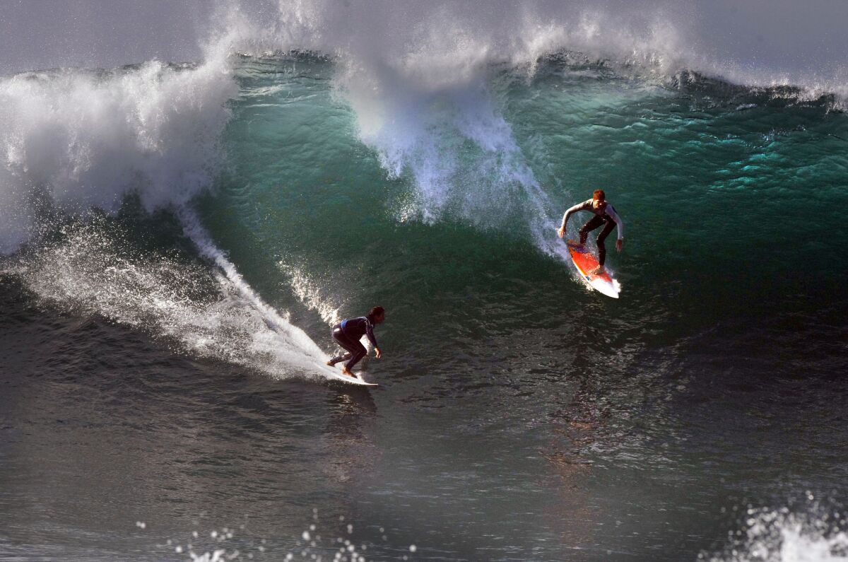 Surfers slide down a huge wave Wednesday at the Wedge in Newport Beach.