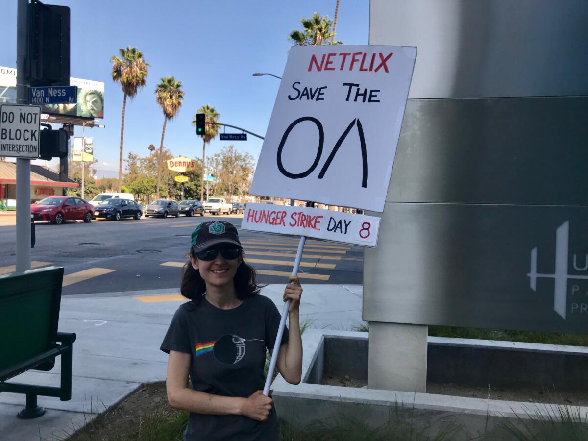 Emperial Young holds her "Save the OA" sign on the corner of Sunset Boulevard and Van Ness in Hollywood outside of the Netflix campus.