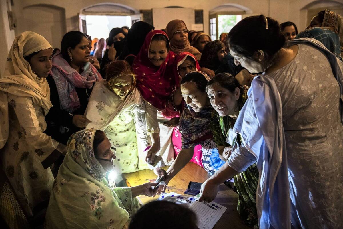 Pakistani women receive ballot papers before casting their votes at a polling station in Lahore. Turnout was high for the country's first democratic transfer of governance.
