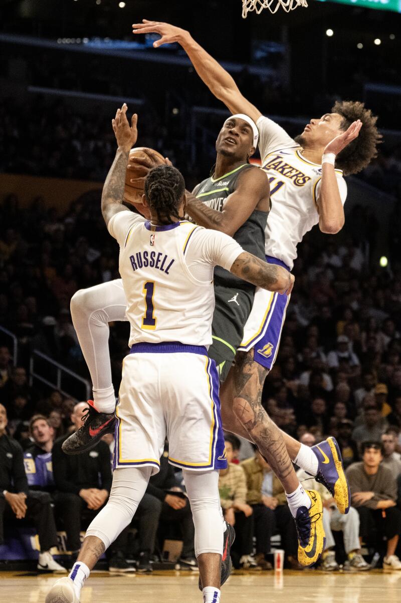 Minnesotalı forvet Jared McDaniels, Lakers'ın pivotu Jaxson Hayes ile guard D'Angelo Russell arasındaki potaya doğru ilerliyor.