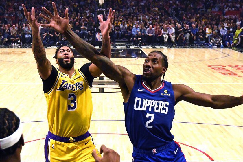 Lakers forward Anthony Davis, left, battles Clippers forward Kawhi Leonard for a rebound during each team's season opener on Oct. 22, 2019.