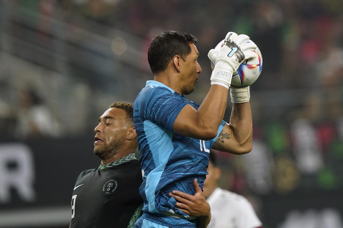 El arquero Rodolfo Cota, de la selección de México, se apodera de un balón junto a Cyriel Dessers,