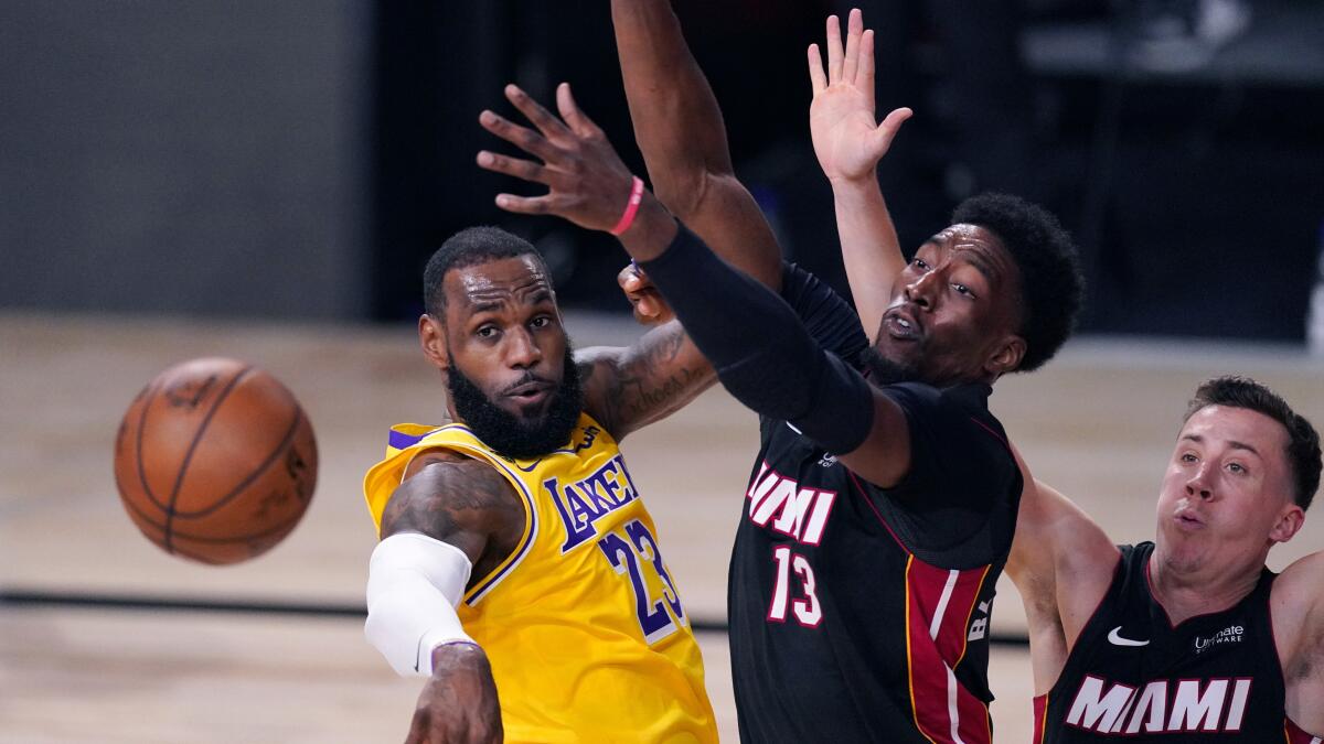 Lakers forward LeBron James passes the ball after being met at the basket by Heat center Bam Adebayo during Game 1..