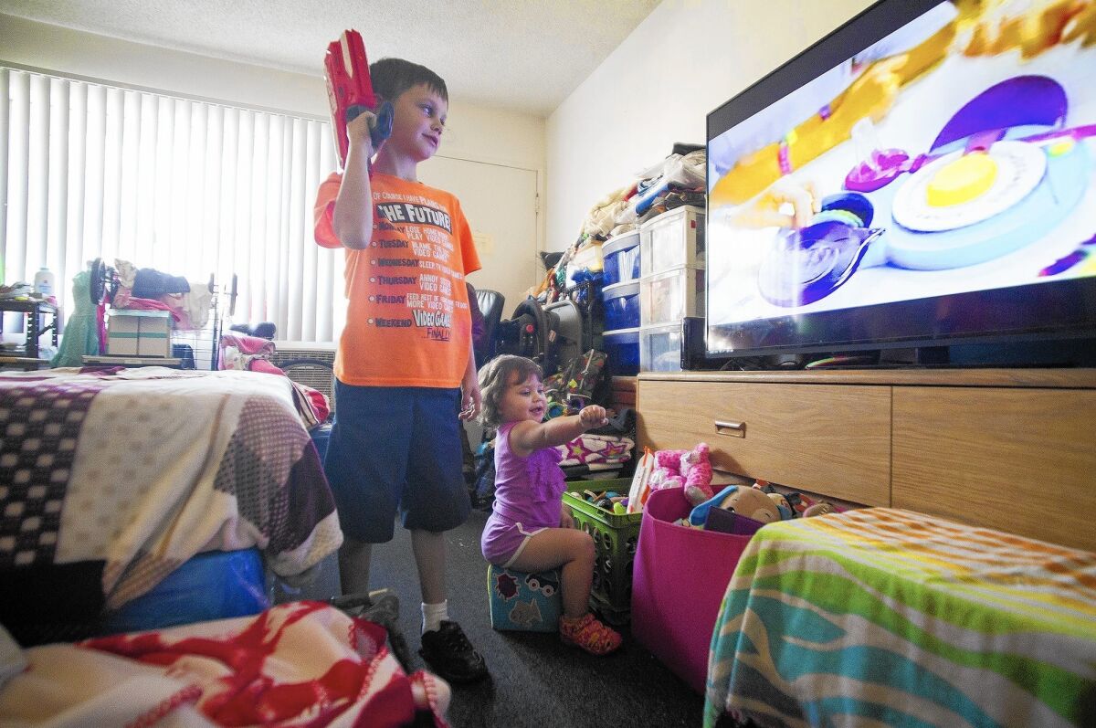 Amanda Haupert's children Scott and Joey play with toys and watch television in their room at the Costa Mesa Motor Inn on Monday. The family has lived at the motel for two years.