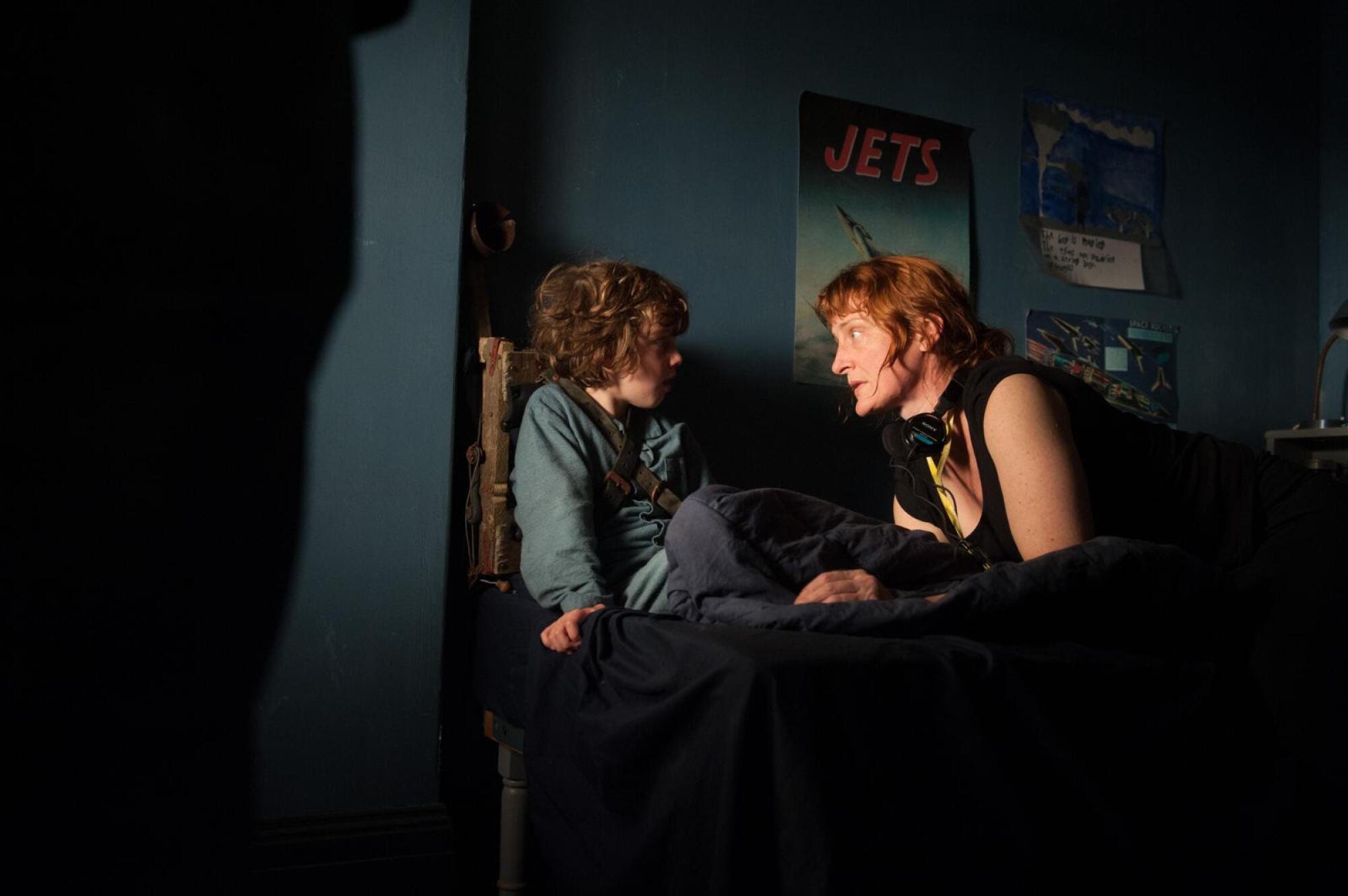 A director gives notes to a young man in bed.