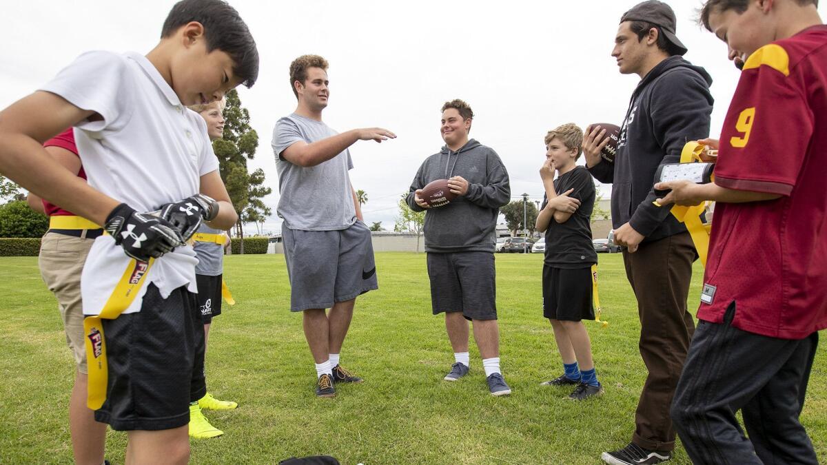 Newport Beach residents Kevin Marheine, center left, and his brother Nick join fellow high school football player Luca de Lancellotti, second from right, in coaching the Bengals of the Matt Leinart Flag Football league.