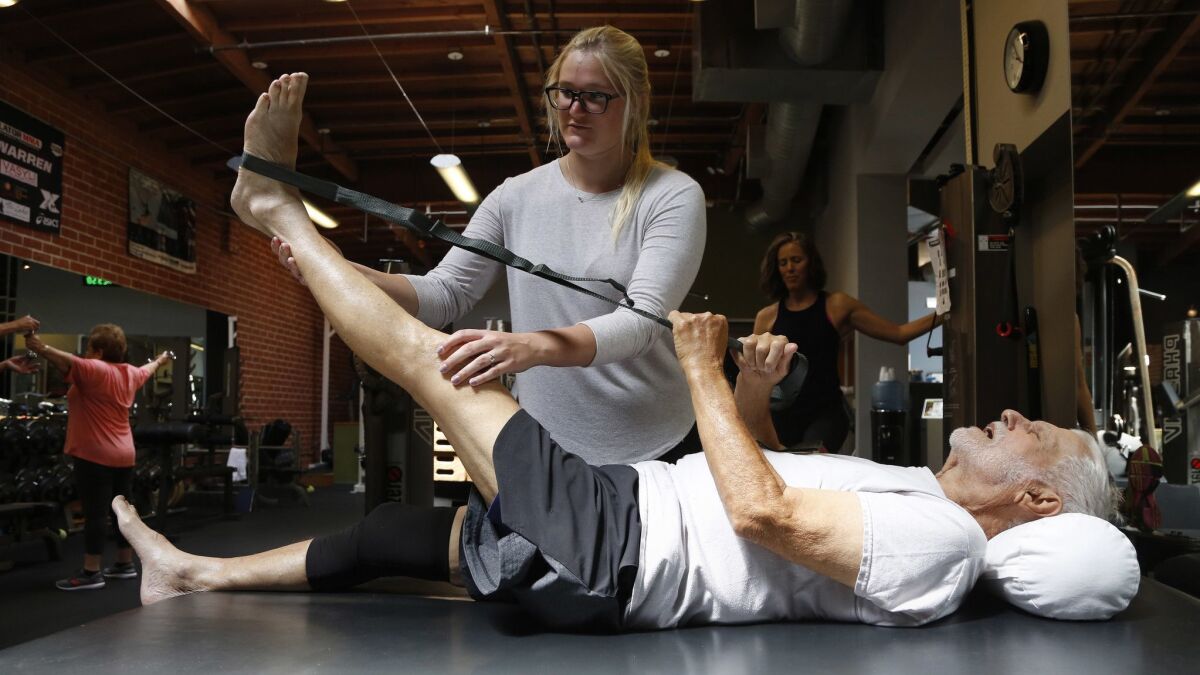 Norman Wallack, age 89, works with exercise physiologist Shelby Stoner, on stretches at Robert Forster PT Phase IV in Santa Monica.