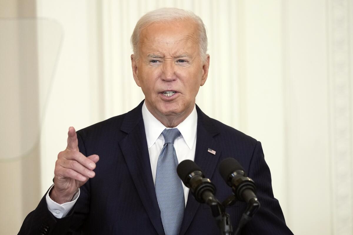 President Biden gestures and speaks into microphones. 