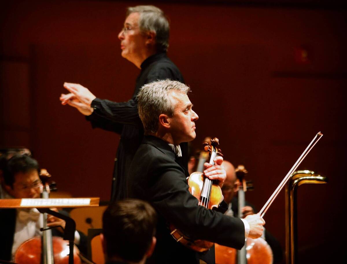 Christian Zacharias, background, conducts the L.A. Philharmonic on Nov. 29, 2013. Concertmaster Martin Chalifour, foreground, is the soloist in a familiar Bach concerto and a small Schubert rarity.