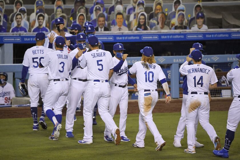 Members of the Los Angeles Dodgers are congratulated by masked coaches after the Dodgers defeated the San Francisco Giants 8-1 in an opening day baseball game, Thursday, July 23, 2020, in Los Angeles. (AP Photo/Mark J. Terrill)