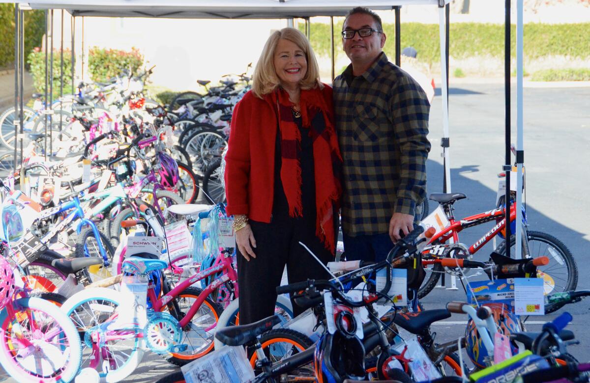 Trish Hurley and Sean Canova pose with 80 bikes on Thursday during the distribution at the Tustin Family Resource Center.