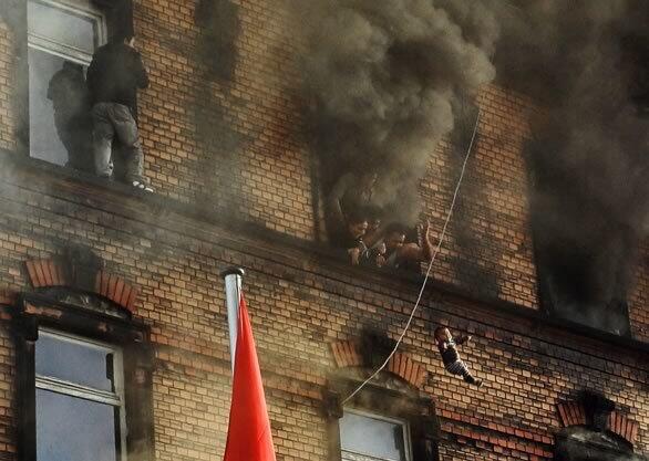 A baby is thrown from a burning building to the fire brigade waiting below in the western German town of Ludwigshafen. The apartment blaze killed nine people, including five children, and injured 28. The child survived.