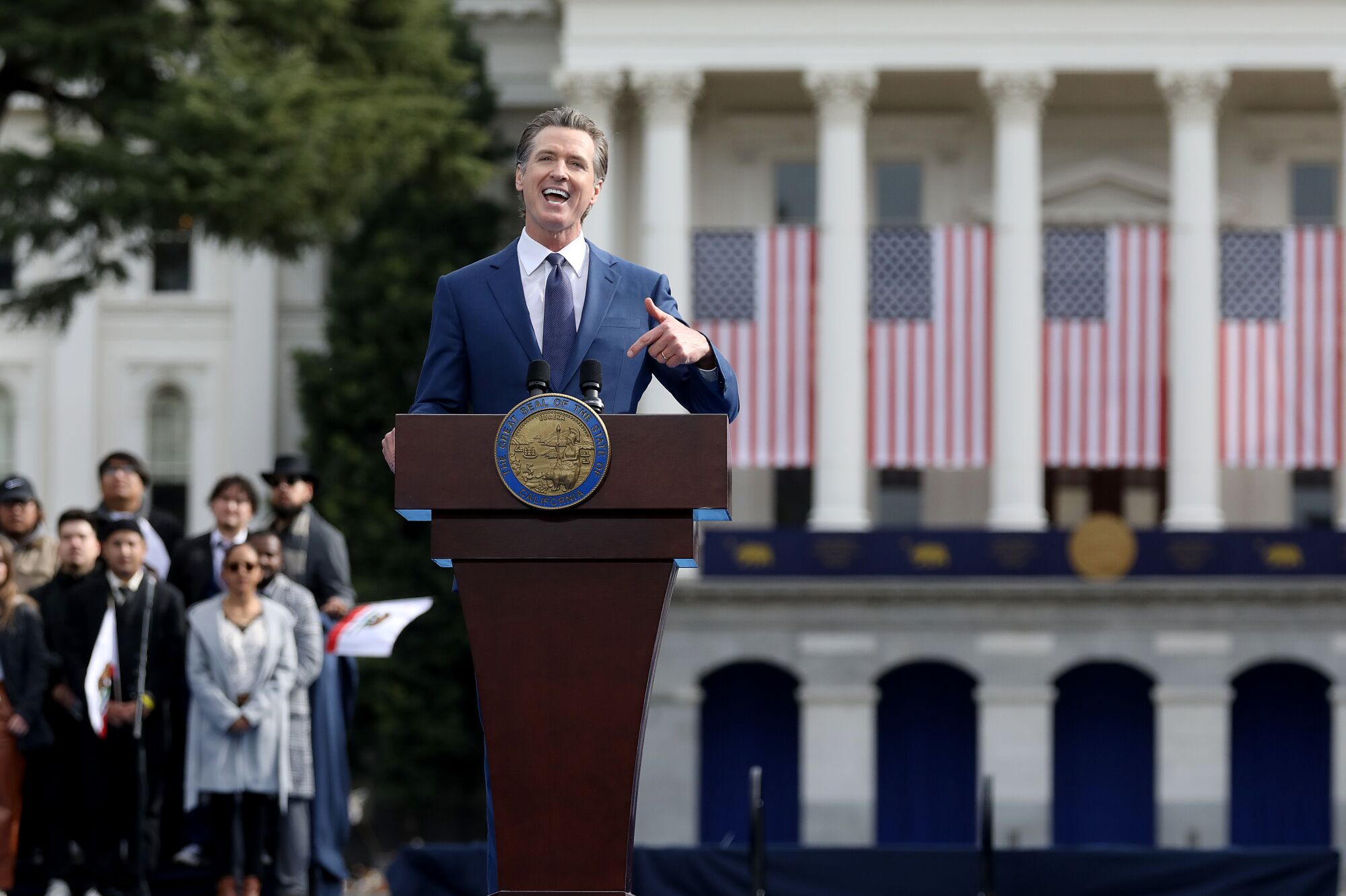 Governor Gavin Newsom smiles as he speaks from a pulpit.