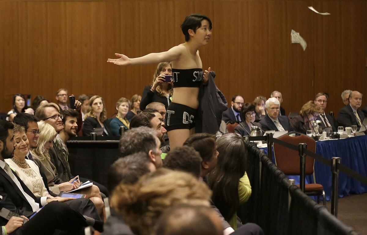 UC Berkeley student Kristian Kim throws fake money while starting a protest during a UC Board of Regents meeting in San Francisco.