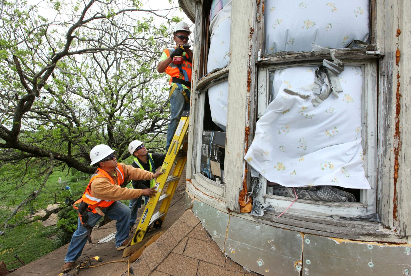 Workers board up windows of a home near the site of the fertilizer plant explosion in West, Texas.