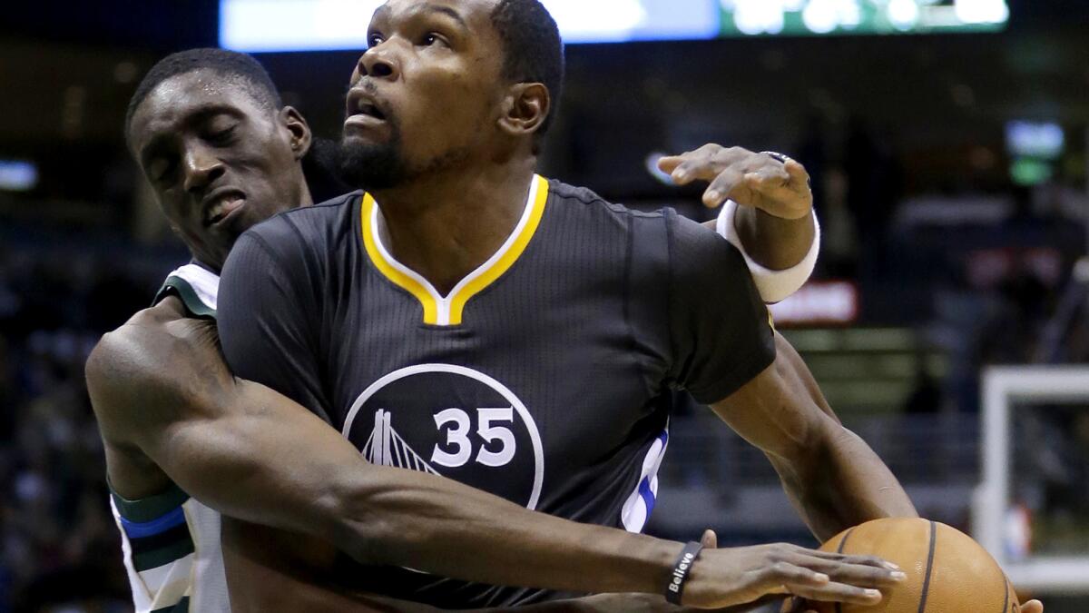 Warriors forward Kevin Durant (35) is fouled by Bucks forward Tony Snell on a drive to the basket in the first half Saturday.