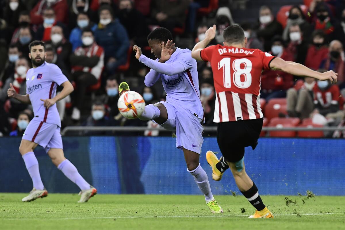 Barcelona's Ansu Fati, center, is challenged by Athletic Bilbao's Oscar de Marcos, right, during the Spanish Copa del Rey Cup round of 16 soccer match between Athletic Club and Barcelona at the San Mames stadium in Bilbao, Thursday, Jan. 20, 2022. (AP Photo/Alvaro Barrientos)