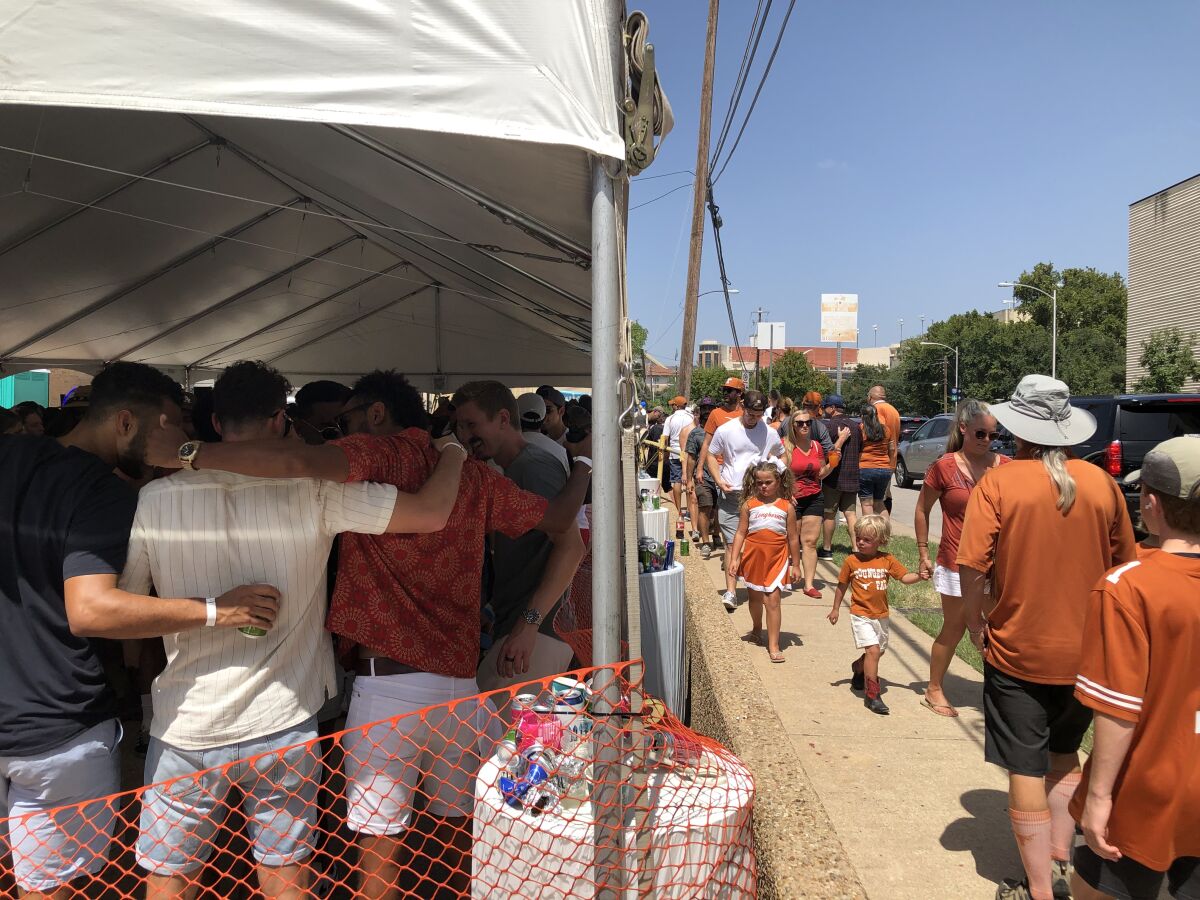 Longhorns fans pass a packed tailgating tent on their way to Saturday's game in Austin, Texas.