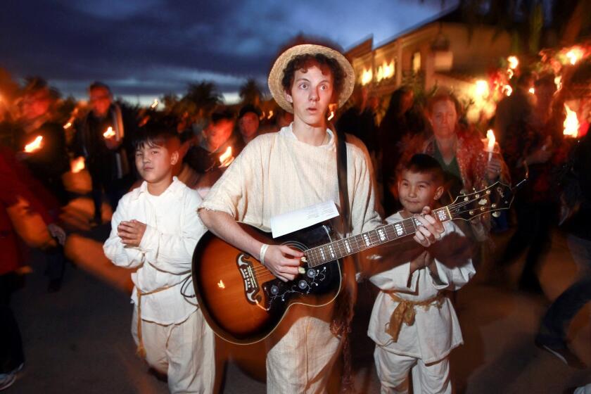 Austyn Myers, 17, sings and plays guitar while he, Eveylt Delger, 10, left, and Eveylt's younger brother Joshua Delger, 8, lead the procession as angels.