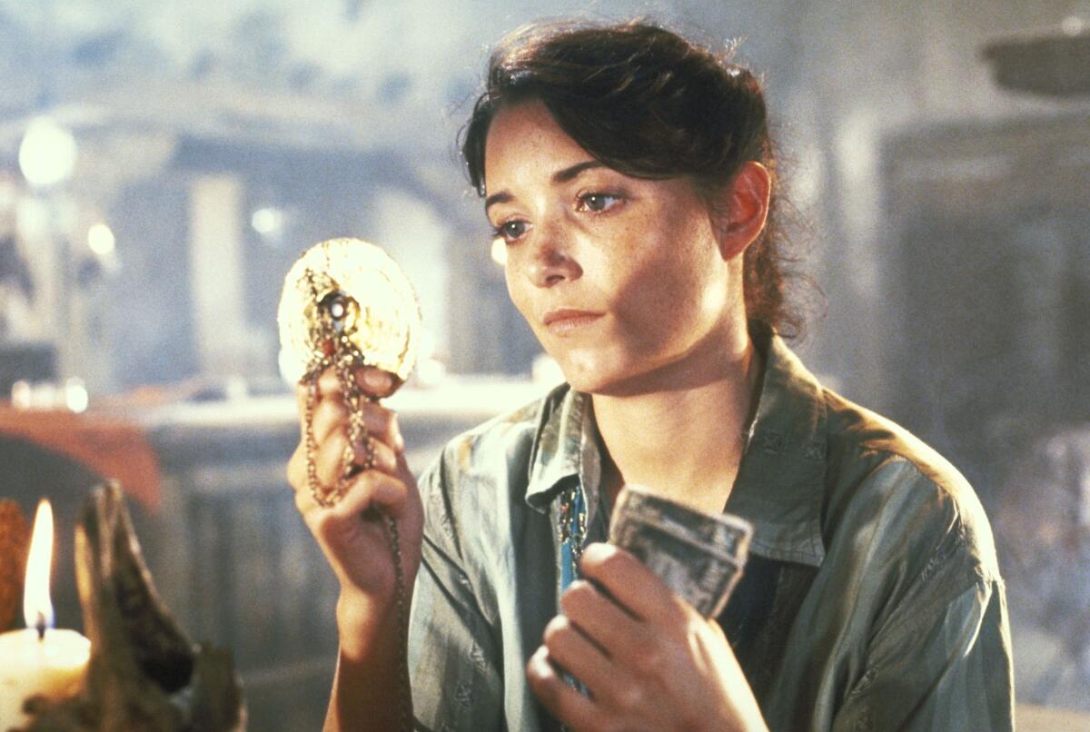 A woman holds cash while looking at a gold archaeological find.