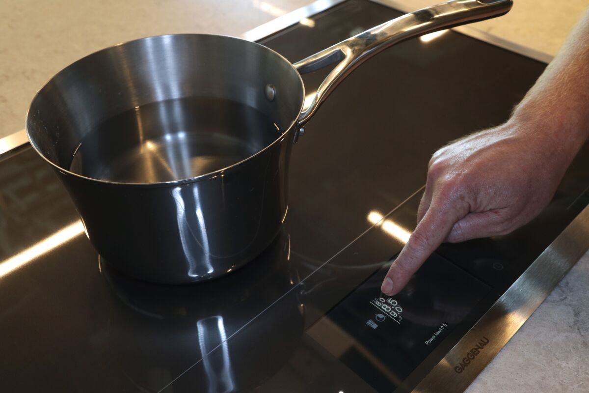 An induction cooktop uses magnetic induction powered with electrical energy to cook food.
