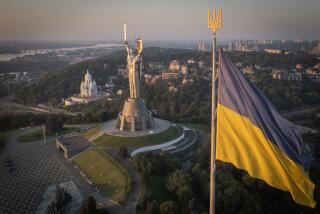 The national flag waves as workers install the Ukrainian coat of arms on the shield in the hand of the country's tallest stature, the Motherland Monument, after the Soviet coat of arms was removed, in Kyiv, Ukraine, Sunday, Aug. 6, 2023. Ukraine is accelerating efforts to erase the vestiges of centuries of Soviet and Russian influence from the public space amid the Russian invasion of Ukraine by pulling down monuments and renaming hundreds of streets to honor home-grown artists, poets, military chiefs, and independence leaders. (AP Photo/Efrem Lukatsky)