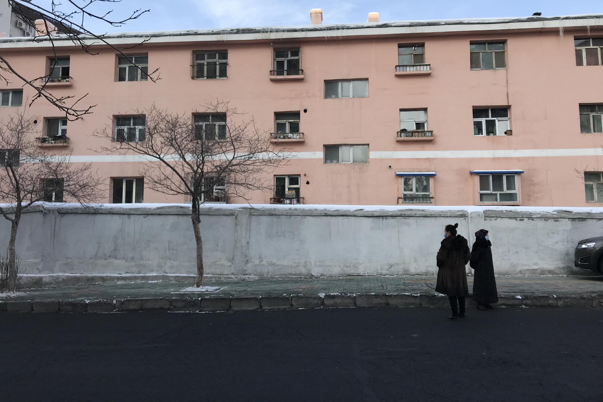 Two women stand on a street.