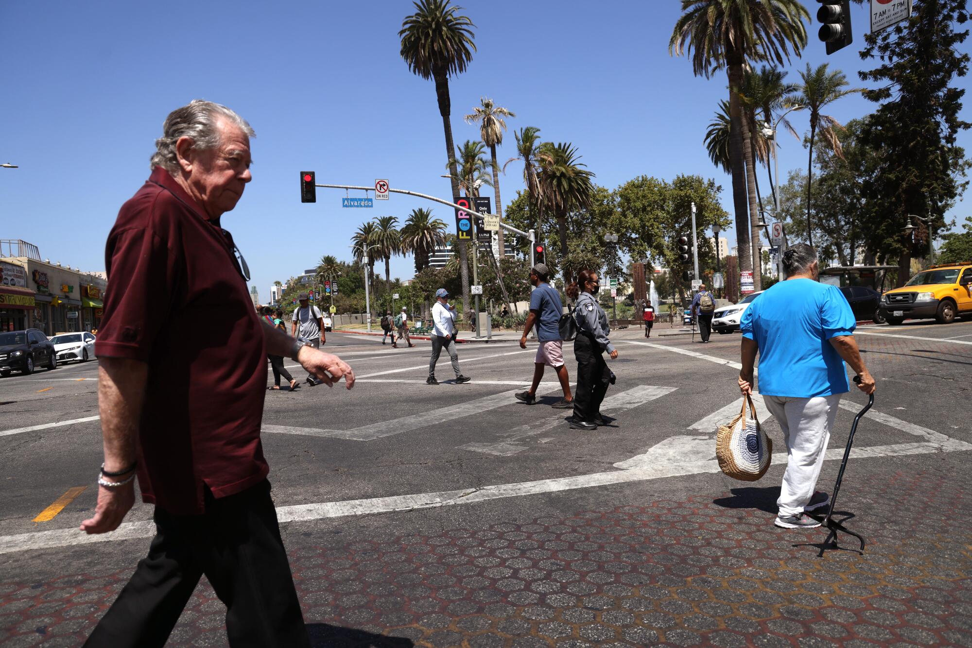 Norm Langer walks down a street near other pedestrians and palm trees.