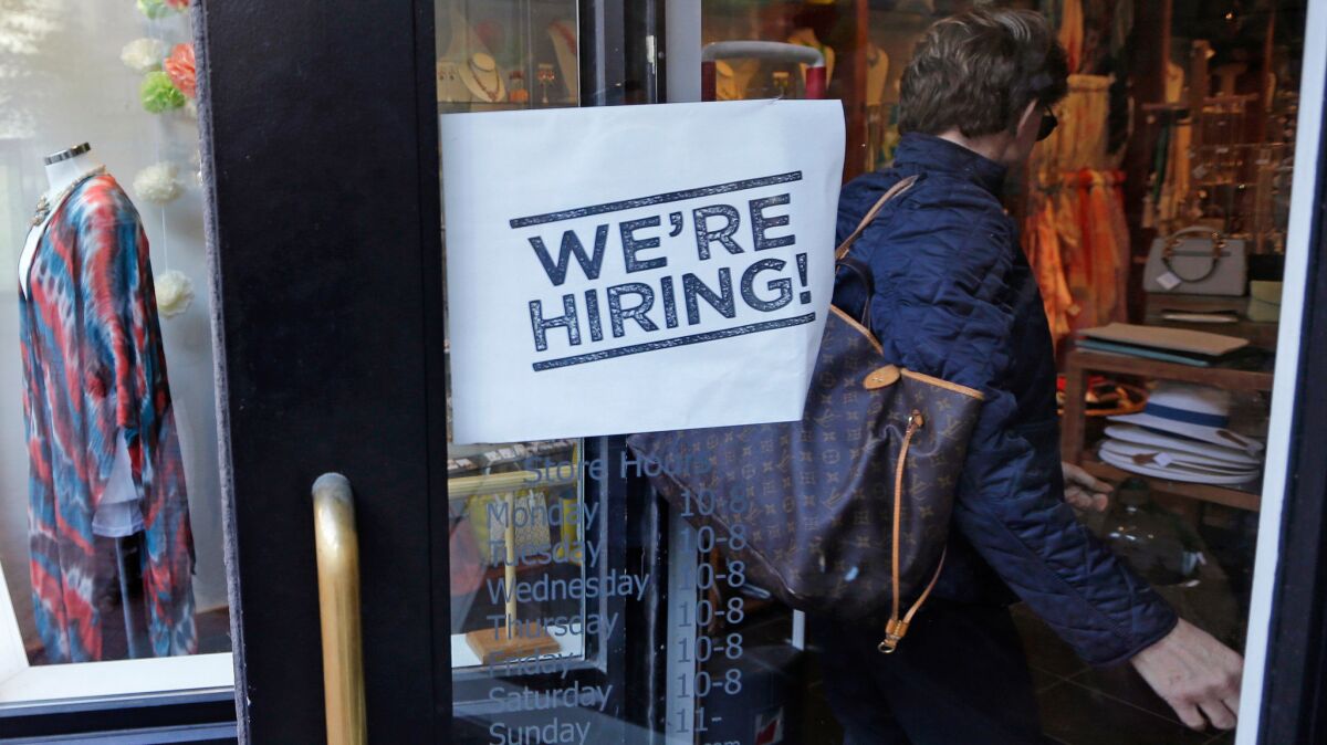 A woman passes a "We're Hiring!" sign while entering a clothing store in the Downtown Crossing of Boston. The U.S. May jobs report raised concerns of the state of the economy.