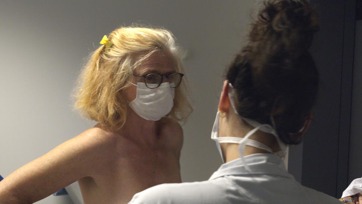 A closeup of woman in a face mask consulting with another woman.