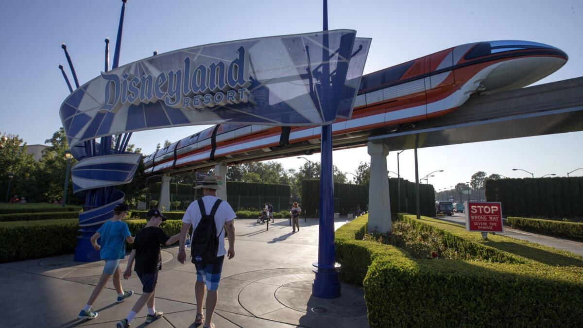 Visitors walk under a Disneyland sign at the theme park in Anaheim. Disney, through a subsidiary, has spent heavily on the upcoming Nov. 6 election in Anaheim.