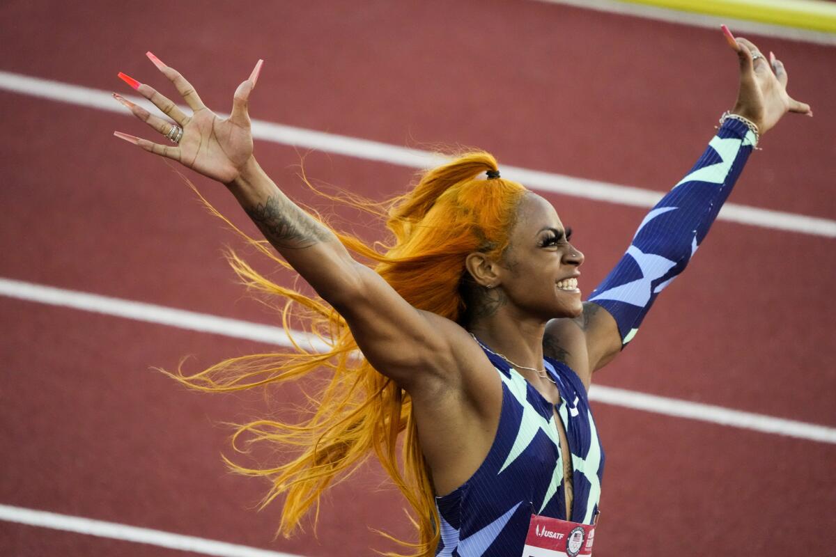 Sha'Carri Richardson, on a track, raises her arms in victory.
