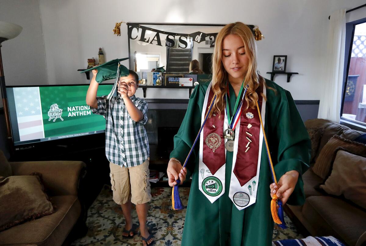 Honor student Jordan Galante dresses in her academic achievements with help from brother Zion who prepares her cap.