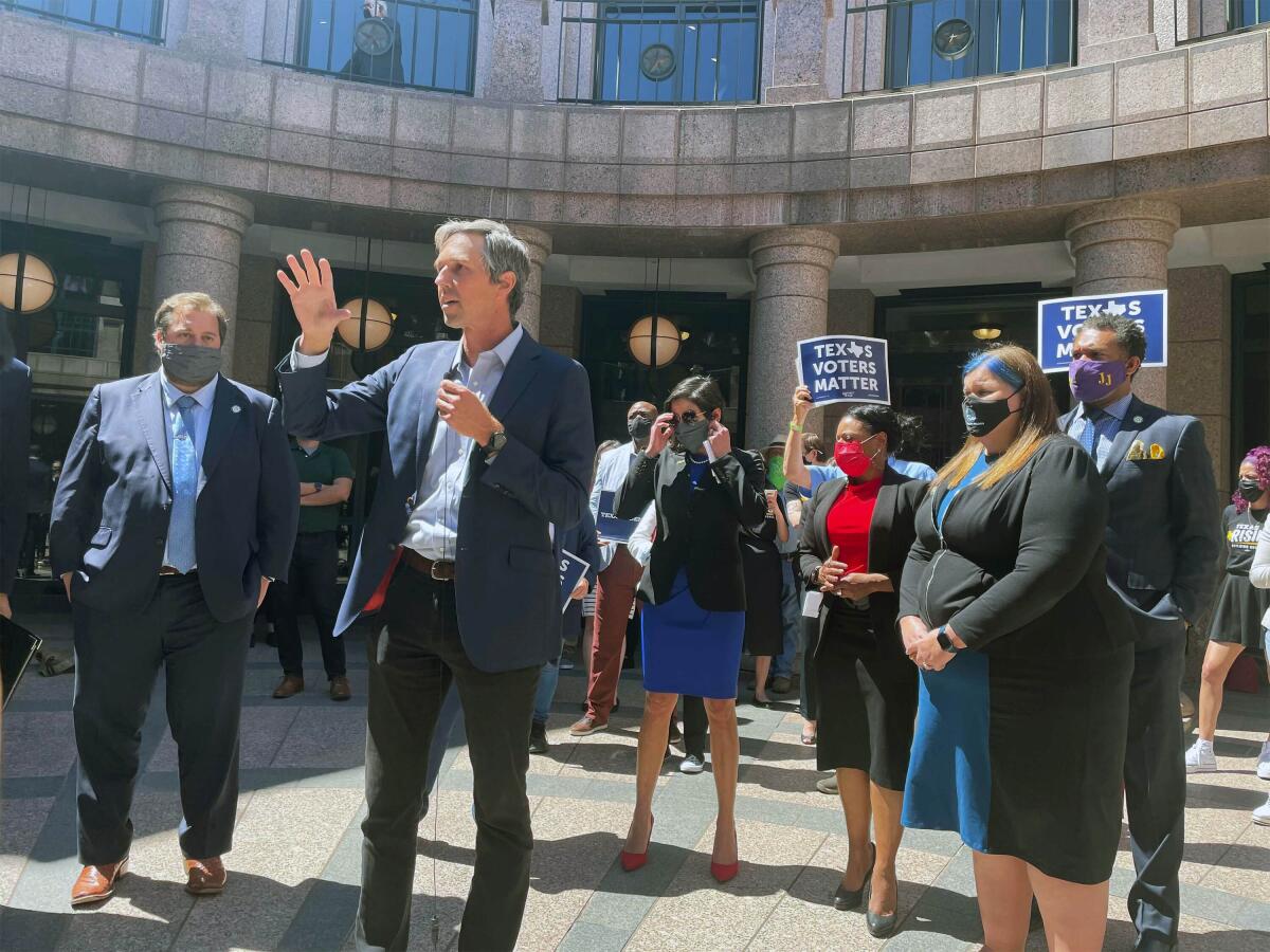 Beto O'Rourke speaks in front of a group of people, some with signs that say Texas voters matter